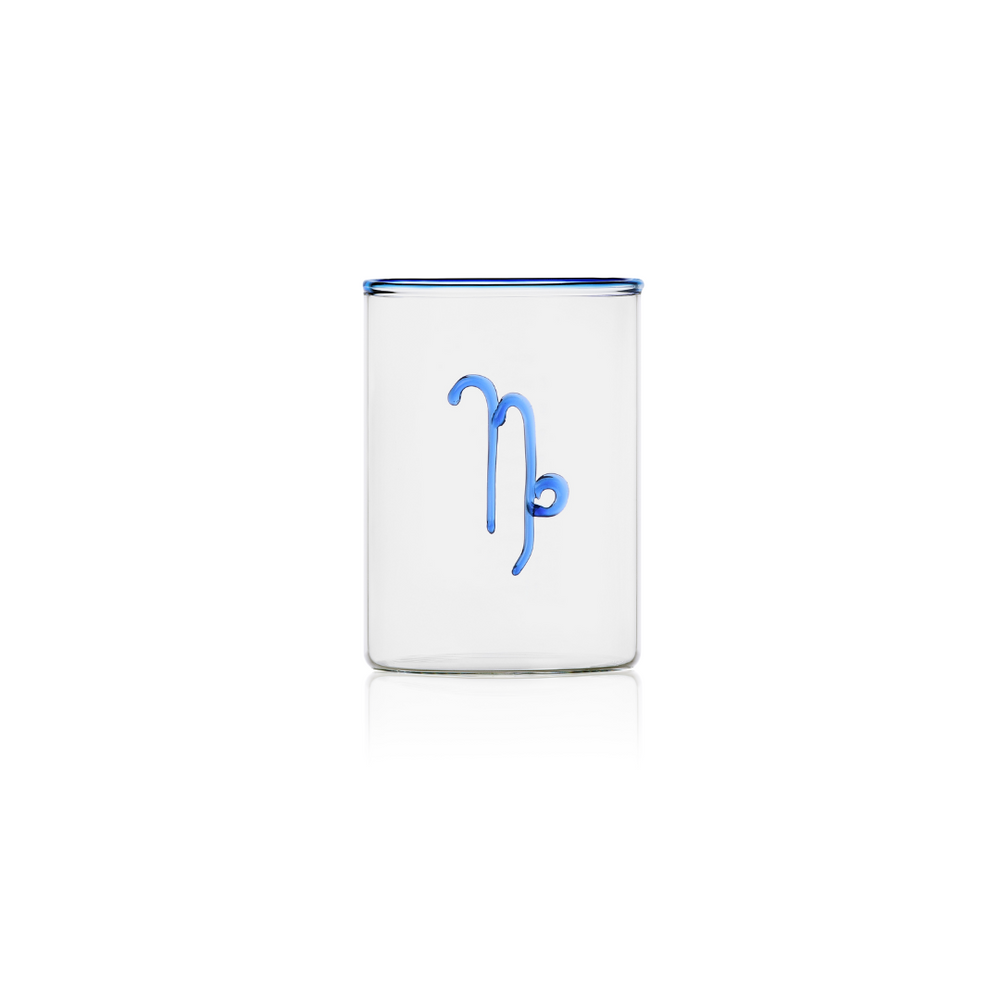 This handblown clear rocks glass with a Capricorn sign on the outside in cobalt blue glass brings just the right amount of colour to the table. The perfect gift under $50  Crafted of borosilicate glass, which is prized for its durability and resistance to thermal shock, this Zodiac Tumbler has a cobalt blue glass rim to add a cheerful yet elegant touch to any occasion.