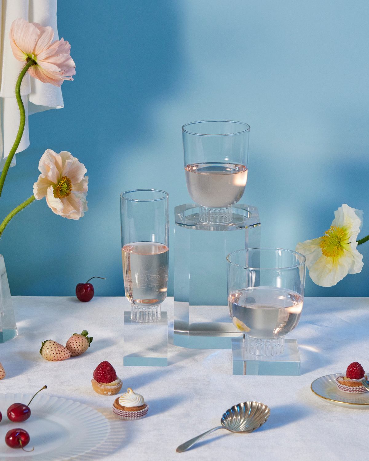 Sprezz clear romantic champagne flute, cocktail glass, and stemless wine glass filled with rose surrounded by flowers, fruits, and dessert. These glasses are lead-free, dishwasher safe and stackable. The fluted bottoms lend a touch of effortless elegance to any party or dinner table. Made of 100% borosilicate which makes them lightweight yet durable and dishwasher safe