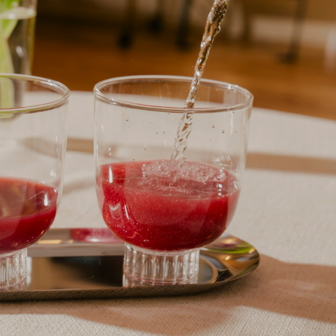 Two lead-free, clear stemless wine glasses containing vibrant red beverages. These hand-blown borosilicate cocktail glasses are the perfect gifts for everyone on your list.