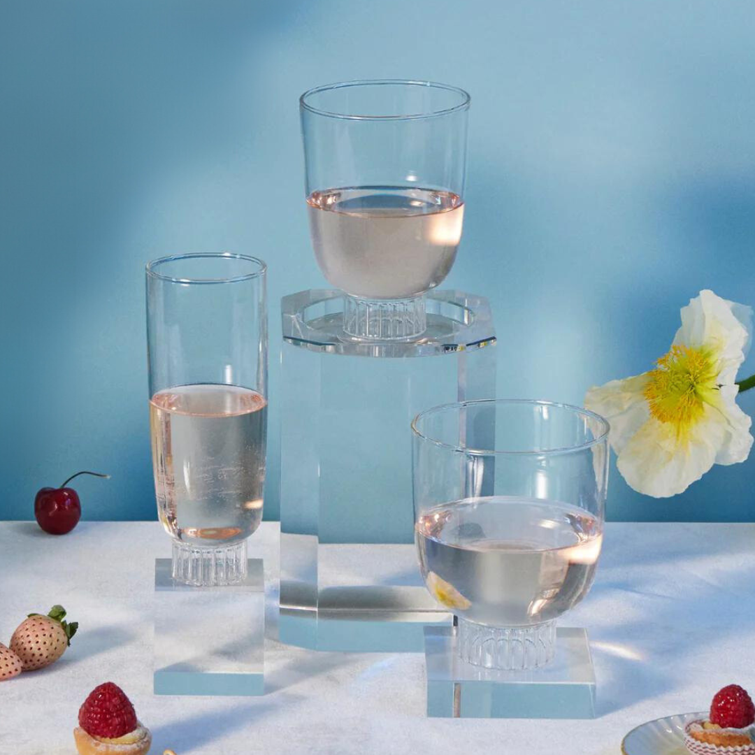 Elegant table setting featuring Sprezz's clear cocktail glasses, stemless wine glasses, and champagne glasses filled with rose. Hand-blown from high-quality, dishwasher-safe, borosilicate glass, these lead-free non-toxic glasses are complemented by an arrangement of fresh flowers, strawberries, and pastries. 