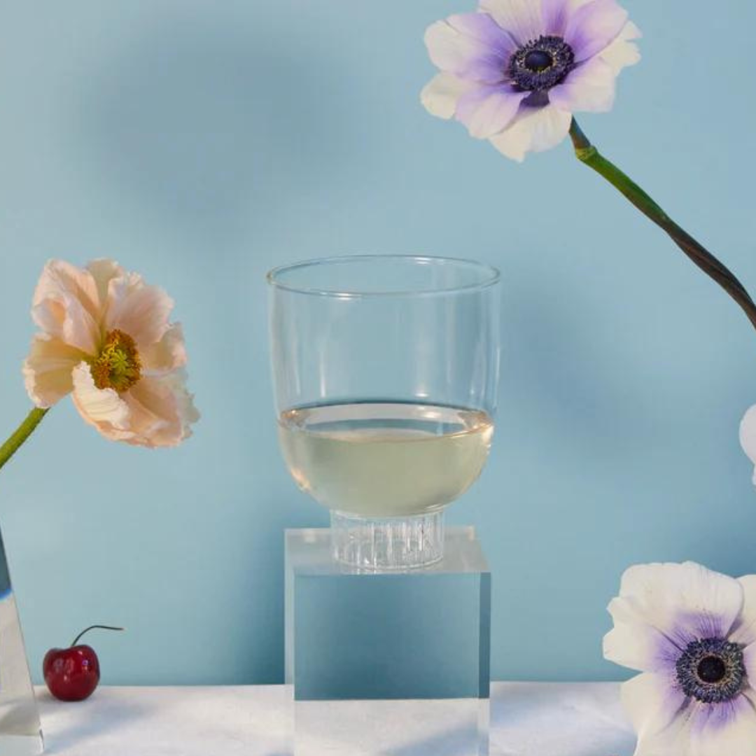 Premium borosilicate cocktail glass by Sprezz, on an elegant dinner table. This non-toxic and dishwasher-safe glassware is paired with a stunning arrangement of pink poppies and anemones. This rocks glass is a perfect blend of form and function for the seasoned host's memorable dinner party.