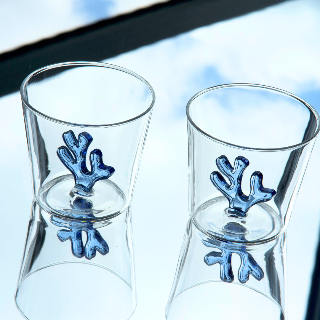 Two Sprezz colored glass drinkware with two blue corals on the inside. A collection of all-purpose clear coloured glassware in cobalt blue