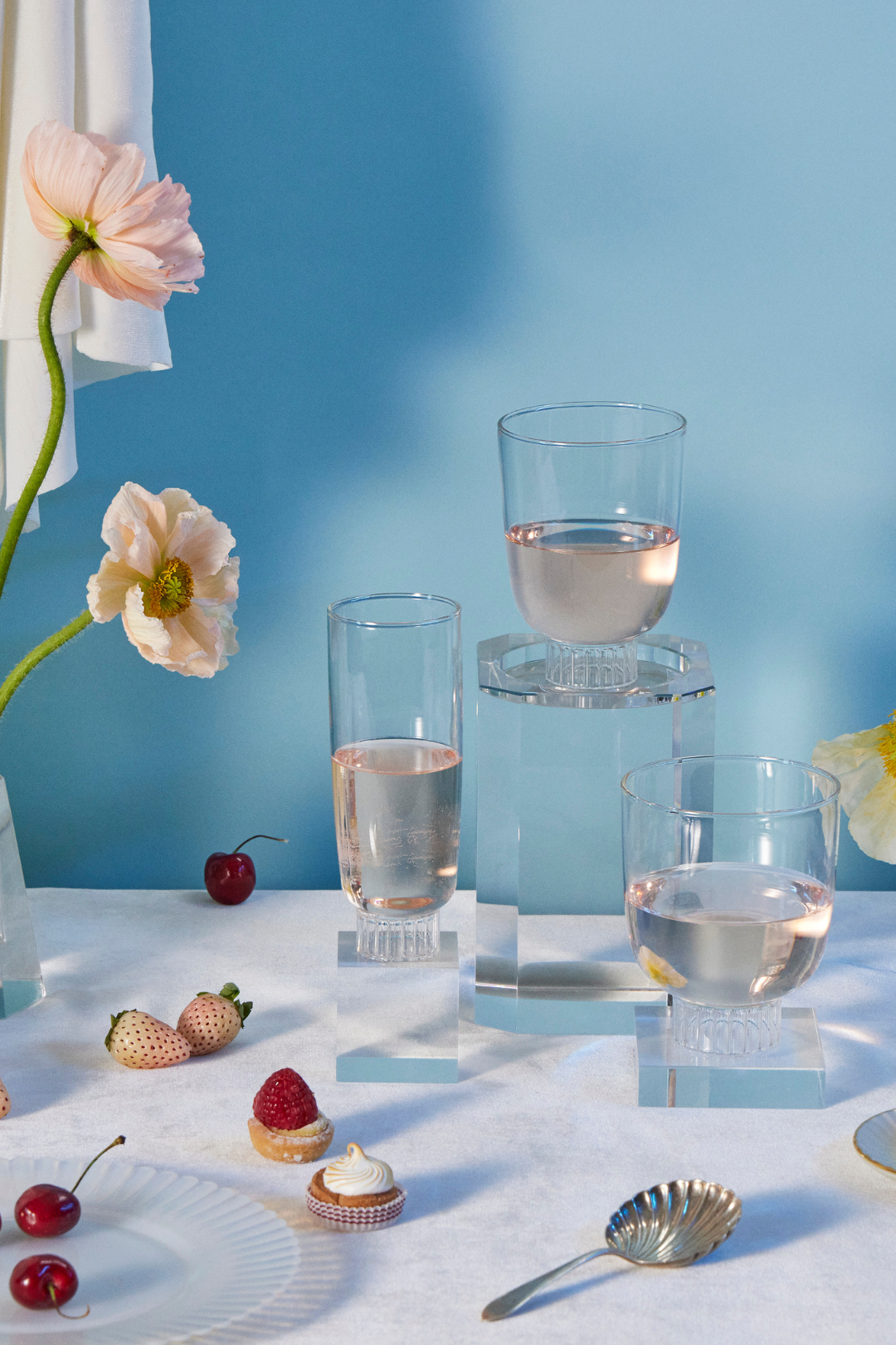 Sprezz clear romantic champagne flute, cocktail glass, and stemless wine glass filled with rose surrounded by flowers, fruits, and dessert. These glasses are lead-free, dishwasher safe and stackable. The fluted bottoms lend a touch of effortless elegance to any party or dinner table.