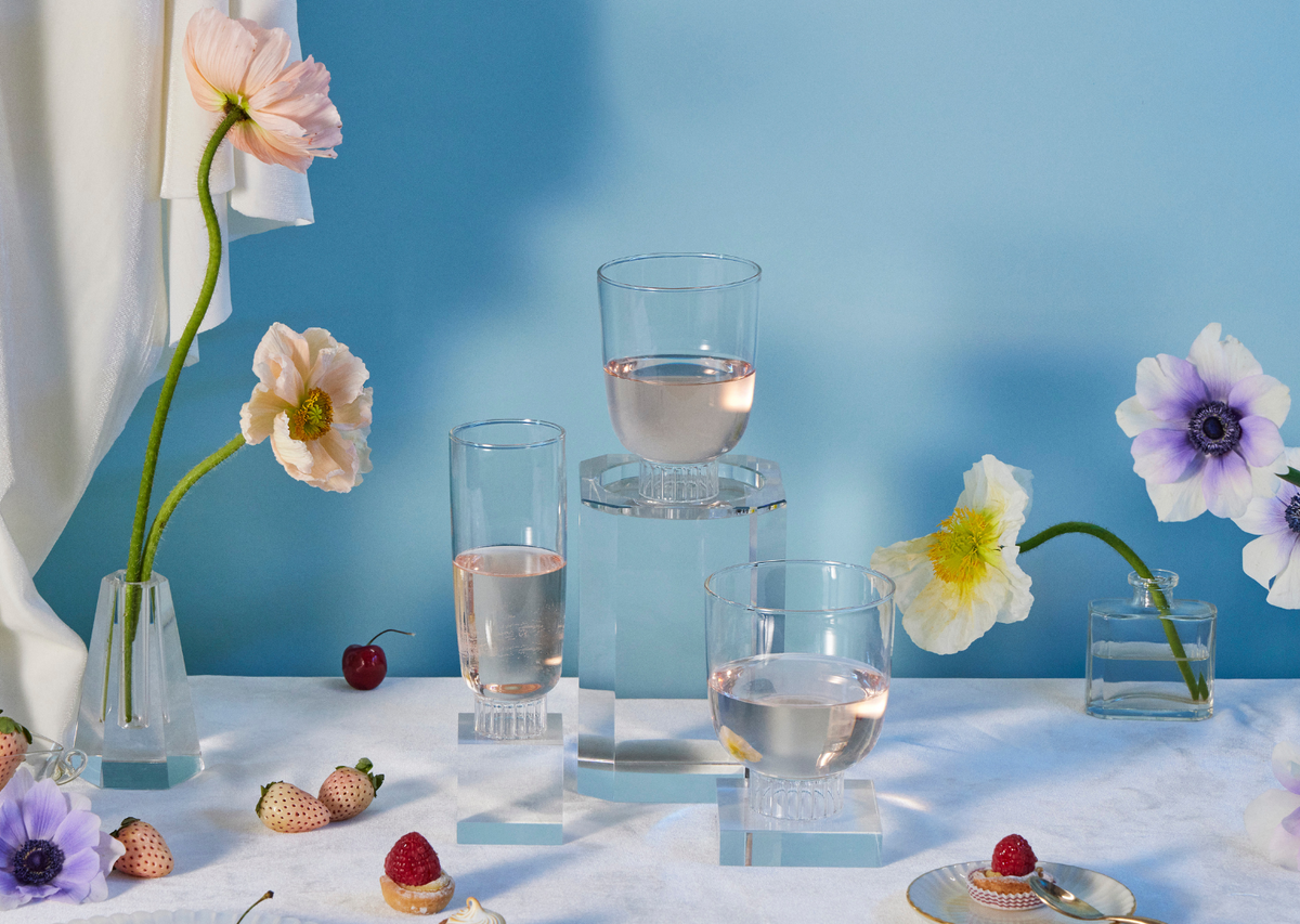 Elegant table setting featuring Sprezz's clear cocktail glasses, stemless wine glasses, and champagne glasses filled with rose. Hand-blown from high-quality, dishwasher-safe, borosilicate glass, these lead-free non-toxic glasses are complemented by an arrangement of fresh flowers, strawberries, and pastries. 